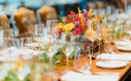 banquet table set with glassware, plates, silverware and decorative flowers